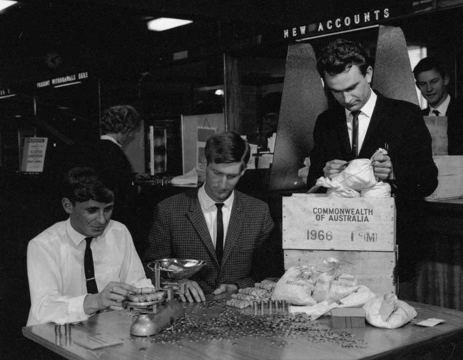 Black and white photo of men counting and weighing coins