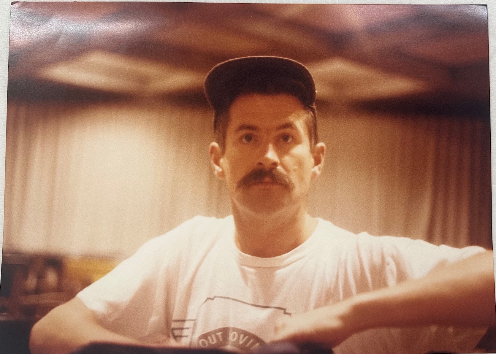 moustached man wearing a white t-shirt and hat