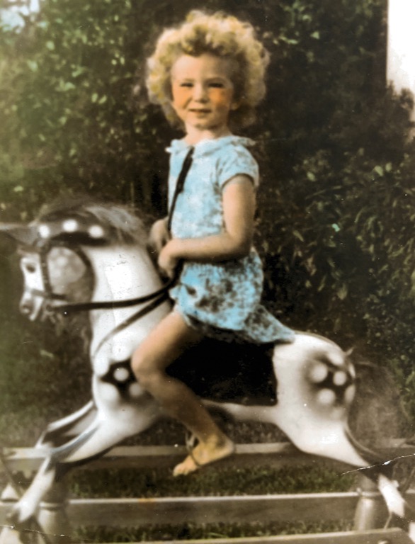 colourised photo of girl on toy horse