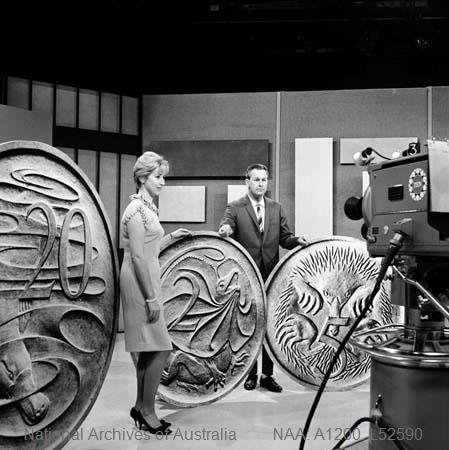 black and white photo showing a man and women with very large models of Australian coins